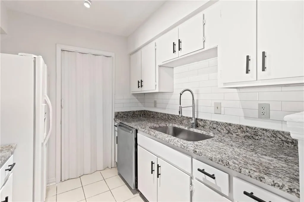 Kitchen featuring sink, white refrigerator with ice dispenser, white cabinets, decorative backsplash, and stainless steel dishwasher