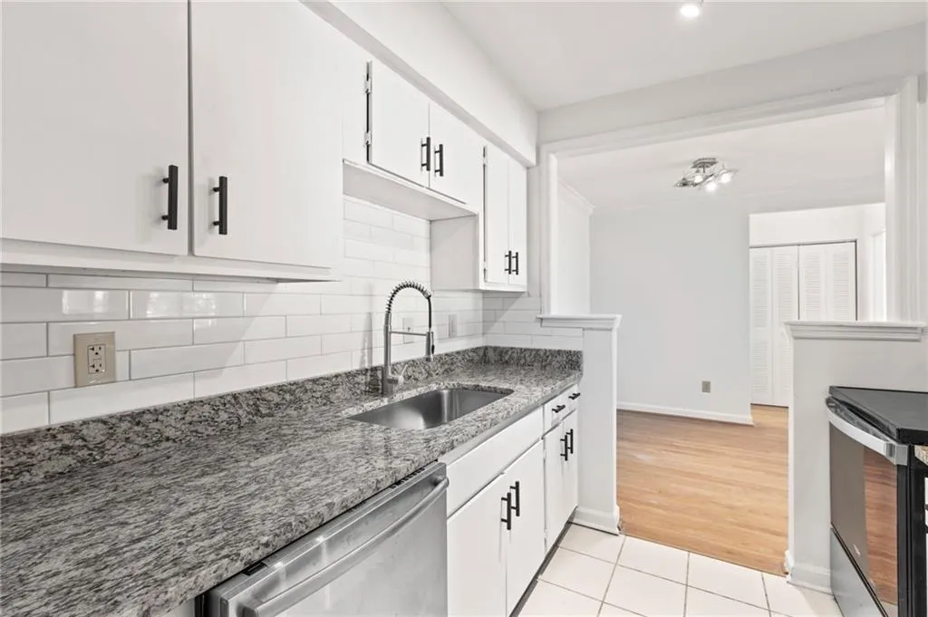Kitchen featuring range with electric cooktop, white cabinetry, sink, stainless steel dishwasher, and light tile patterned floors