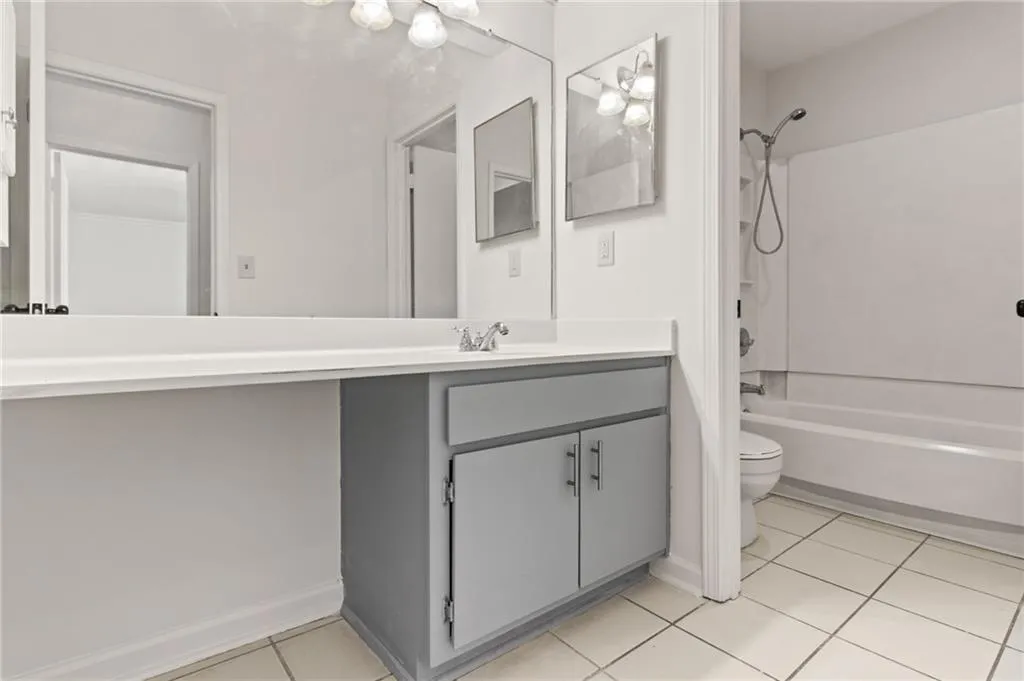 Full bathroom with shower / bath combination, vanity, tile patterned floors, and toilet