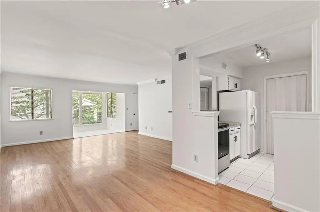 Kitchen with white cabinetry, stainless steel electric range, light hardwood / wood-style flooring, ornamental molding, and white refrigerator with ice dispenser