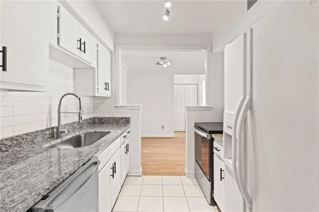 Kitchen with tasteful backsplash, appliances with stainless steel finishes, sink, and white cabinets