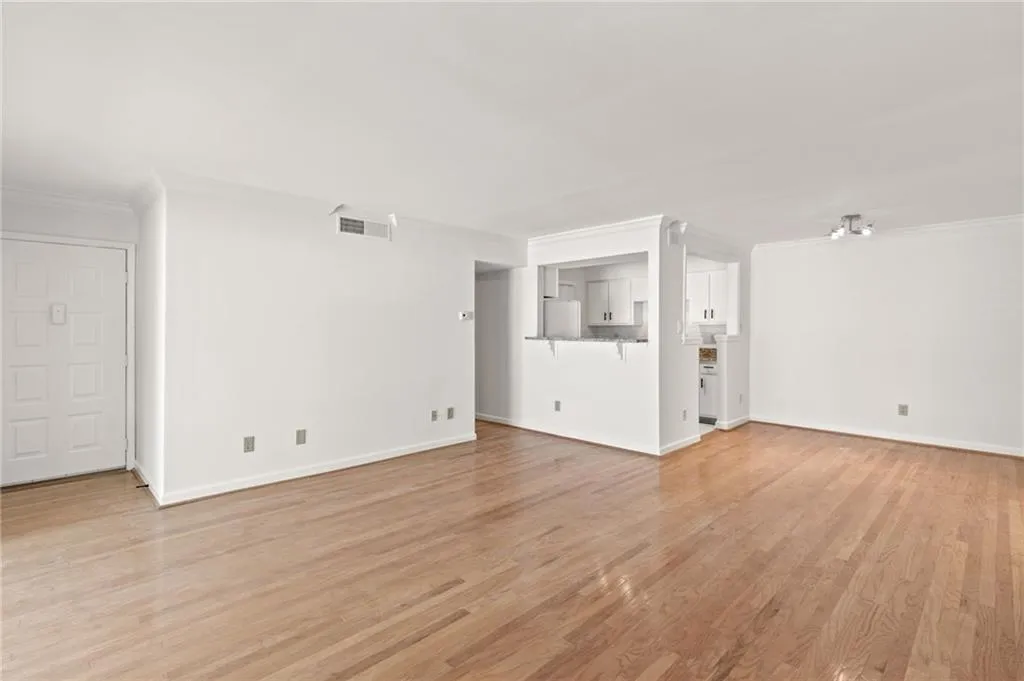 Unfurnished living room with crown molding and light wood-type flooring
