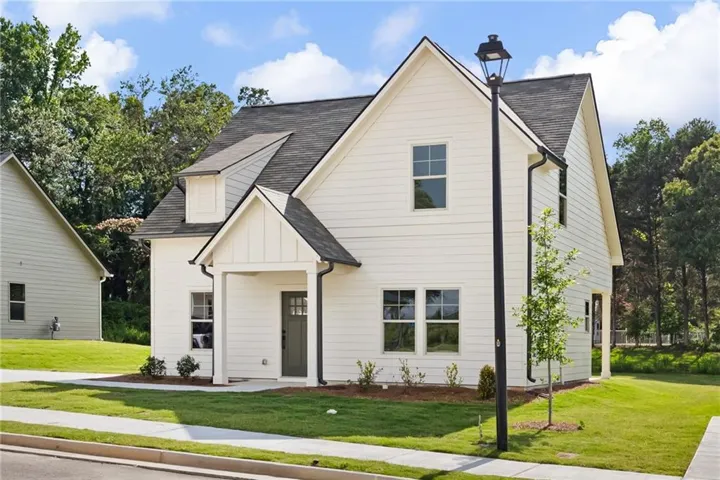 White two-story residence featuring vertical and horizontal siding, a covered porch entry, and dark-framed windows