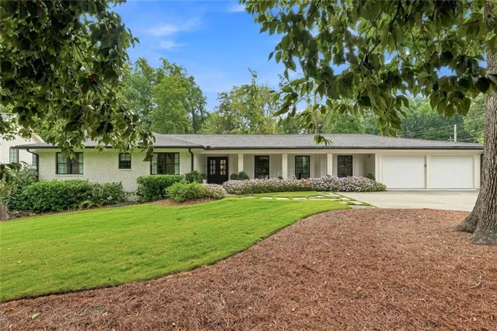 White brick exterior featuring a covered entry porch with columns, a two-car garage, and a concrete driveway
