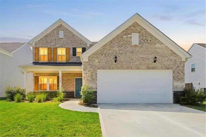 Brick-clad exterior with a two-car garage, covered entry porch, and mature landscaping