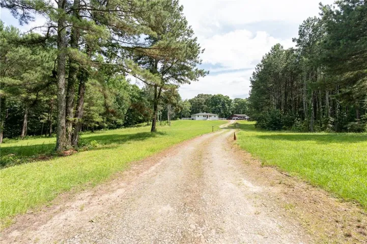 Gravel driveway approaching a white ranch-style residence