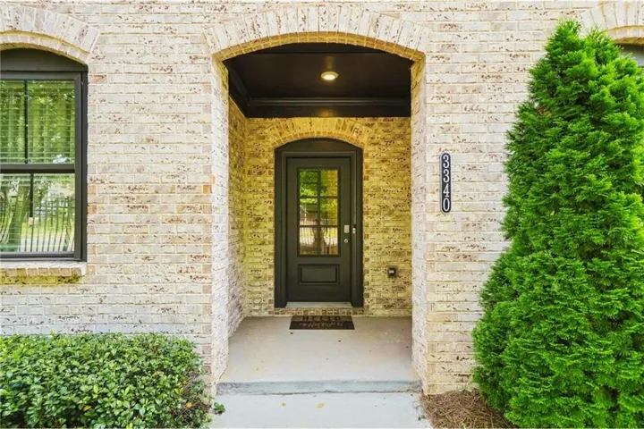 Brick exterior with an arched entry, covered porch, and dark-framed windows