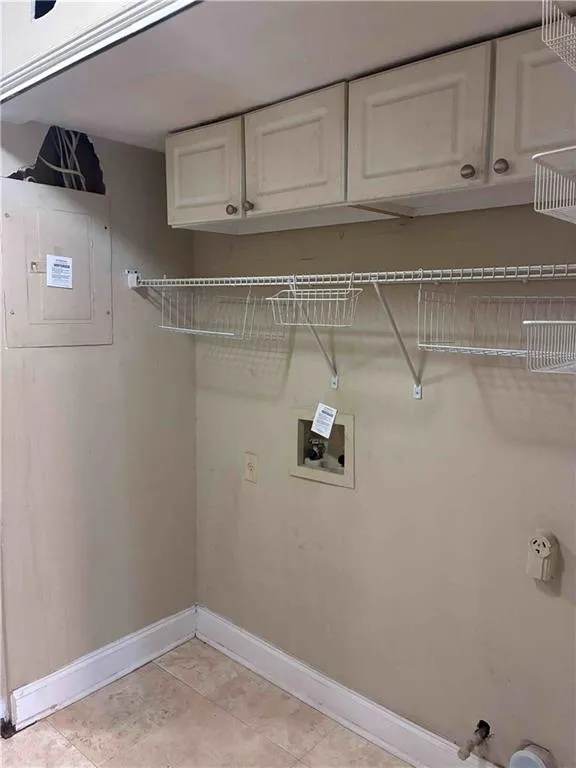 Washroom in the kitchen featuring electric panel, cabinet space, hookup for a washing machine, and light tile patterned floors Washroom in the kitchen featuring electric panel, cabinet space, hookup for a washing machine, and light tile patterned floors