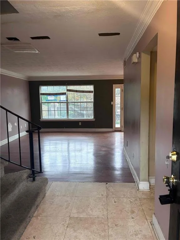 Entryway with crown molding, a textured ceiling, and dark wood flooring