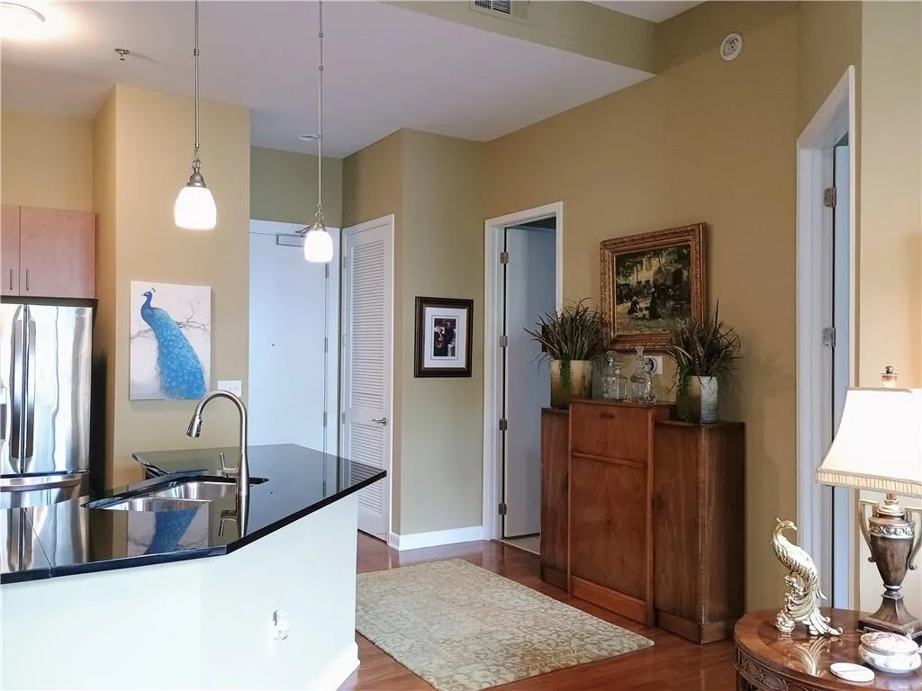 Kitchen with a sink, dark countertops, freestanding refrigerator, dark wood-style flooring, and hanging light fixtures