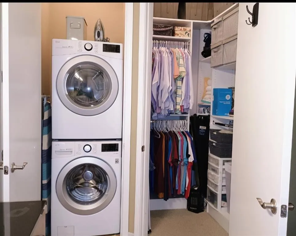 Laundry area with stacked washing maching and dryer, laundry area, and carpet flooring