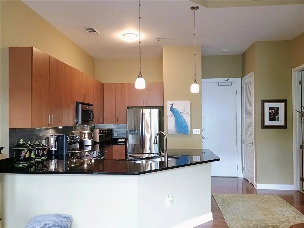 Kitchen featuring tasteful backsplash, a sink, appliances with stainless steel finishes, dark countertops, and a peninsula