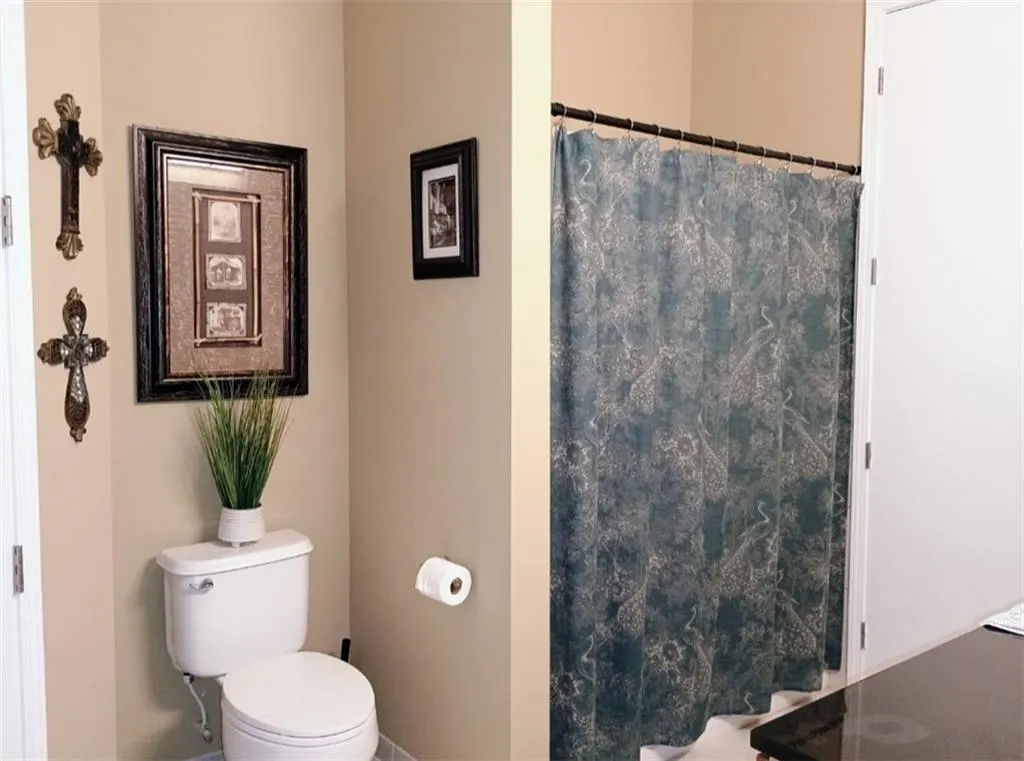 Bathroom featuring toilet, a shower with curtain, and baseboards