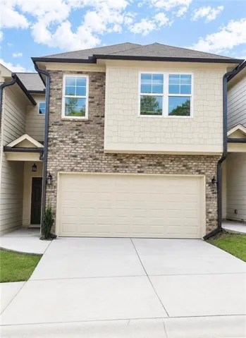 Brick and shingle exterior with a two-car garage, concrete driveway, and covered entry