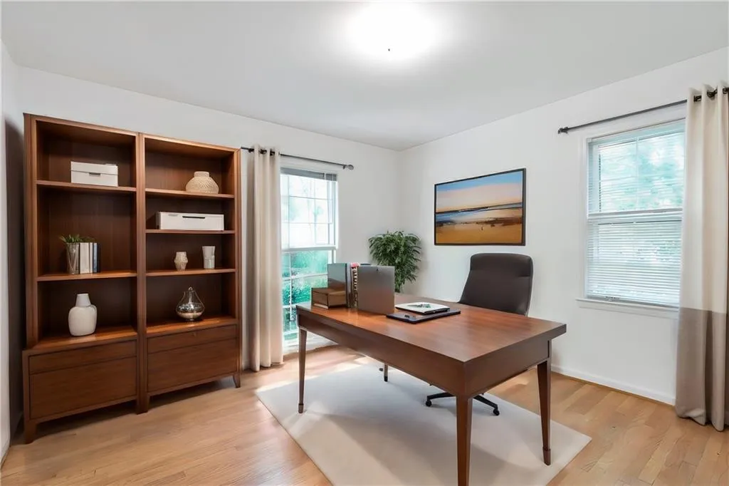 Home office/bedroom featuring light hardwood / wood-style flooring and a wealth of natural light. Virtually staged.