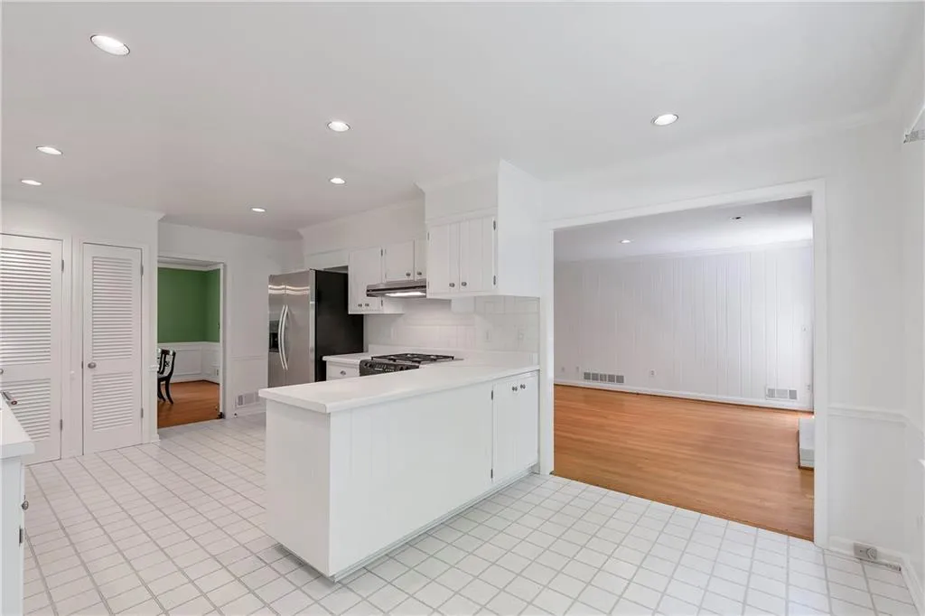 Kitchen featuring white cabinetry, range, backsplash, stainless steel refrigerator with ice dispenser, and light tile flooring
