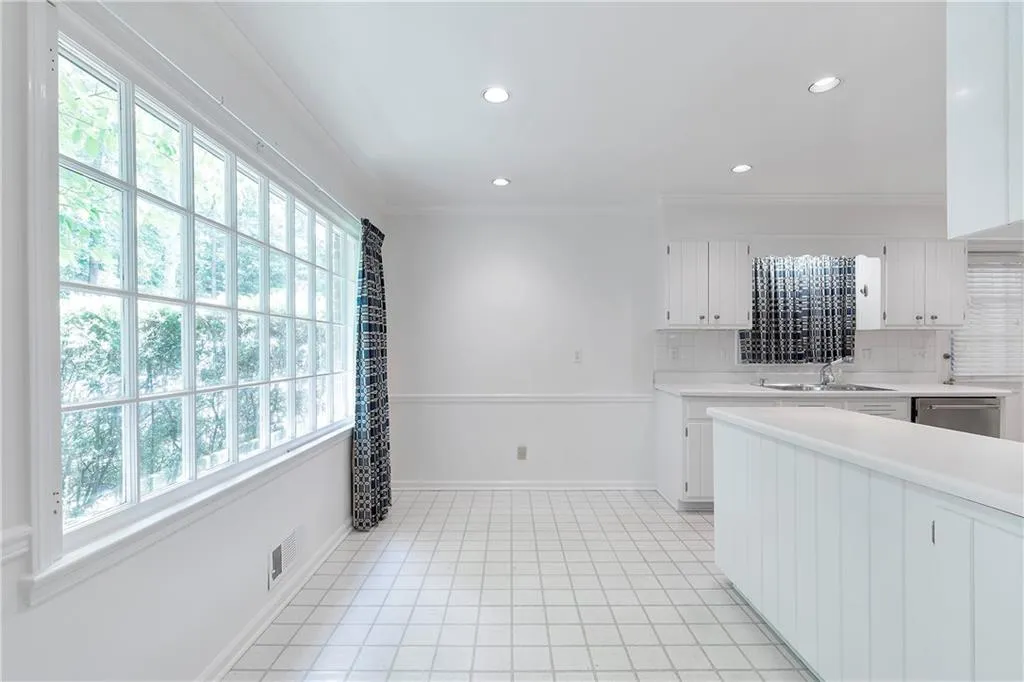 Kitchen with a healthy amount of sunlight, white cabinets, tasteful backsplash, and light tile floors