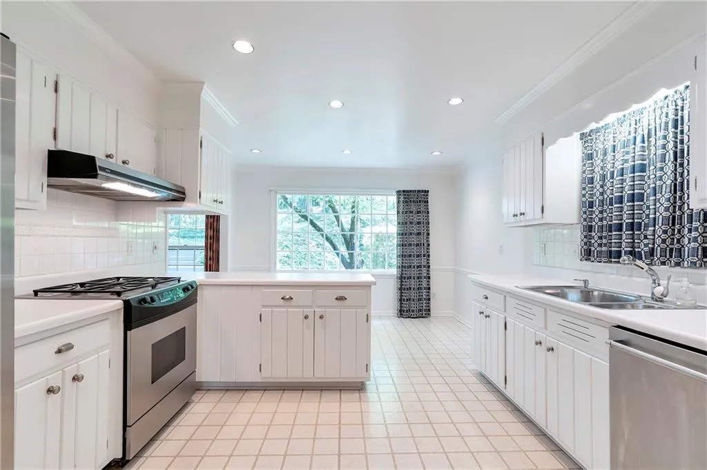 Kitchen with appliances with stainless steel finishes, white cabinetry, sink, and tasteful backsplash