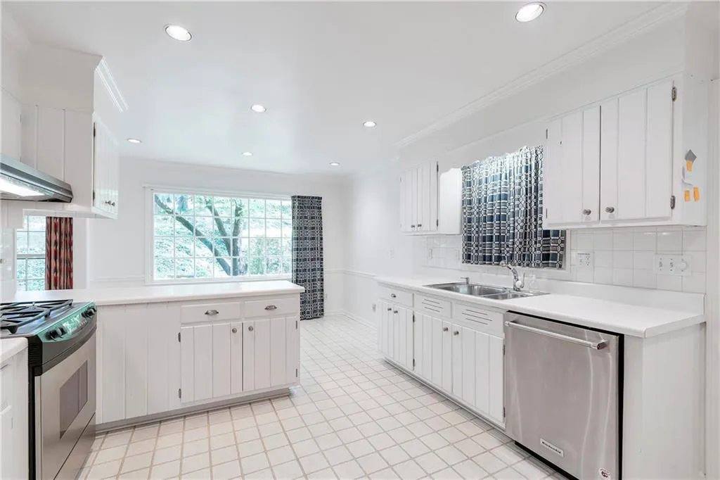 Kitchen with backsplash, light tile flooring, gas range oven, and stainless steel dishwasher