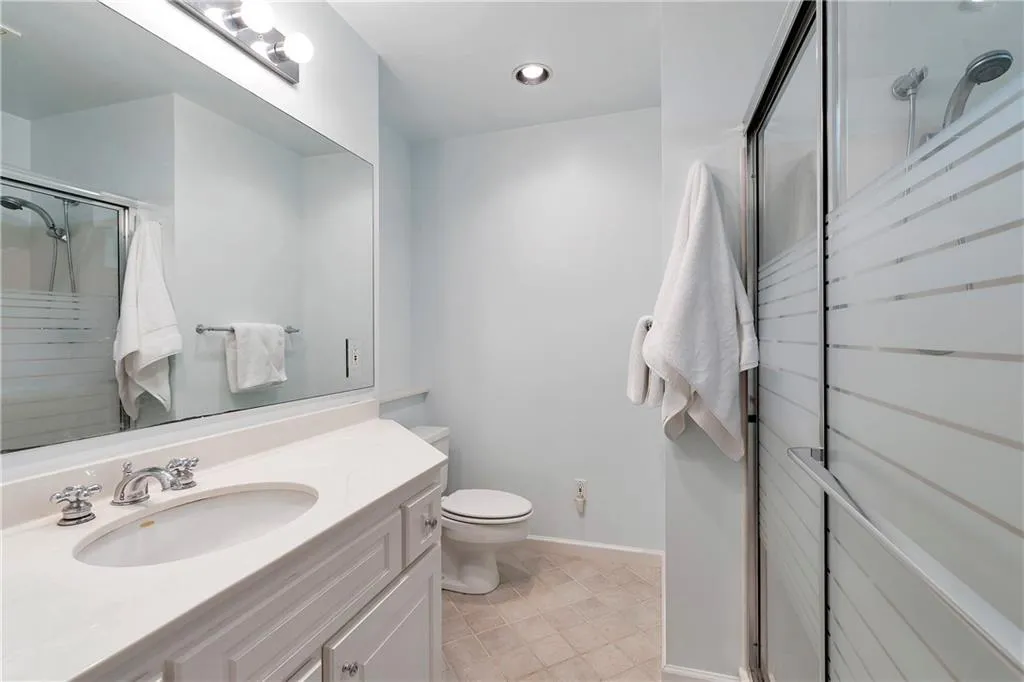 Bathroom with tile floors, a shower with door, toilet, and large vanity