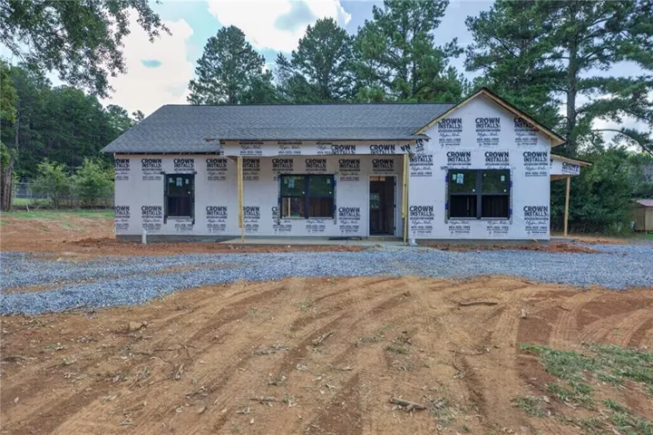 New construction residence with an unfinished exterior, featuring a gray shingle roof and multiple windows