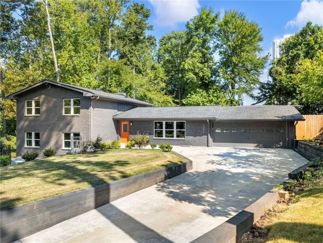 Split Level residence featuring brick construction, a two-car garage, and a dual driveway access with retaining walls