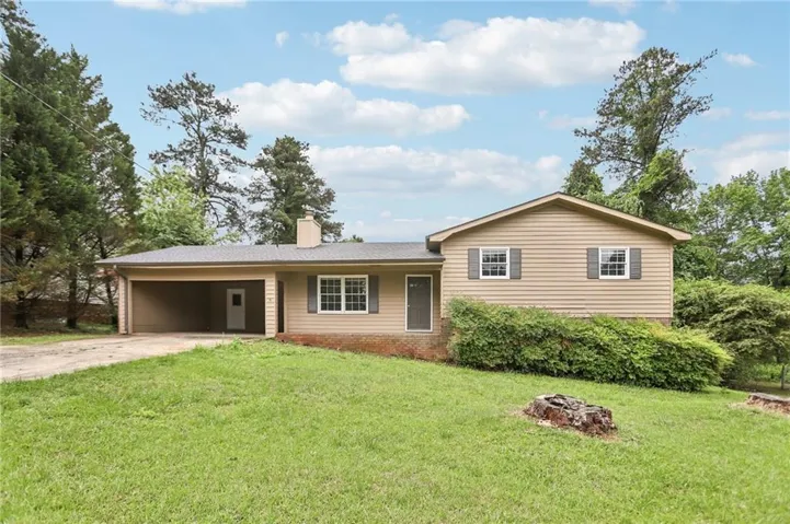 Ranch-style residence featuring a carport, horizontal siding, dark shutters, and a sloped front yard