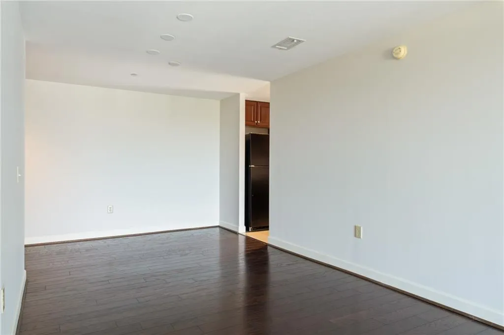 Spacious room with dark wood-finish flooring, white walls, and recessed ceiling lighting