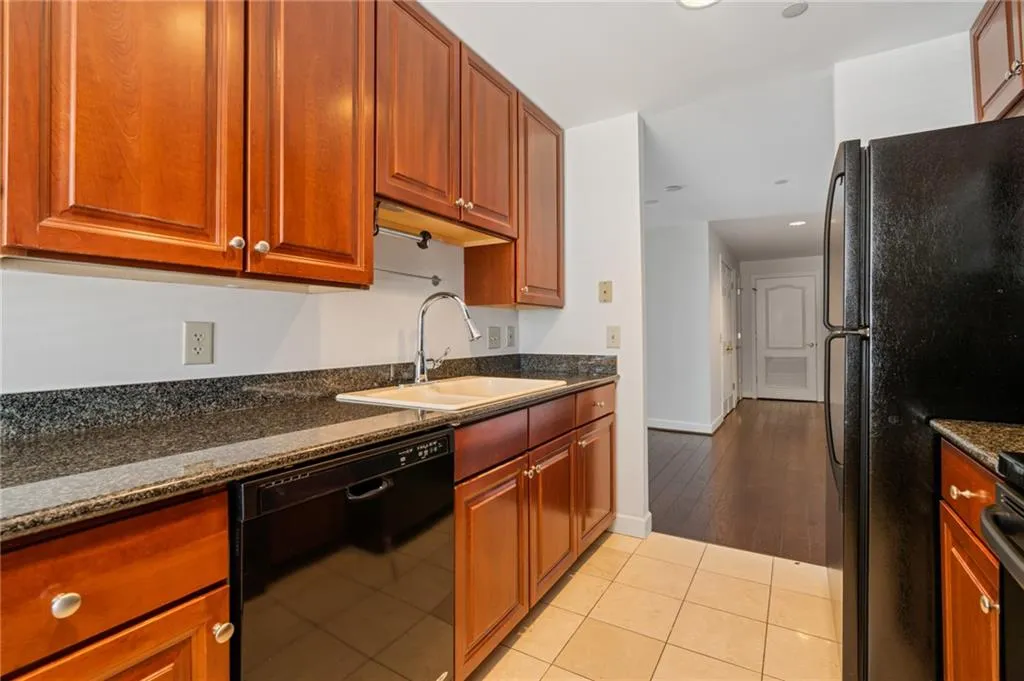 Kitchen featuring wood cabinetry, dark-finish countertops, and stainless steel sink with a gooseneck faucet