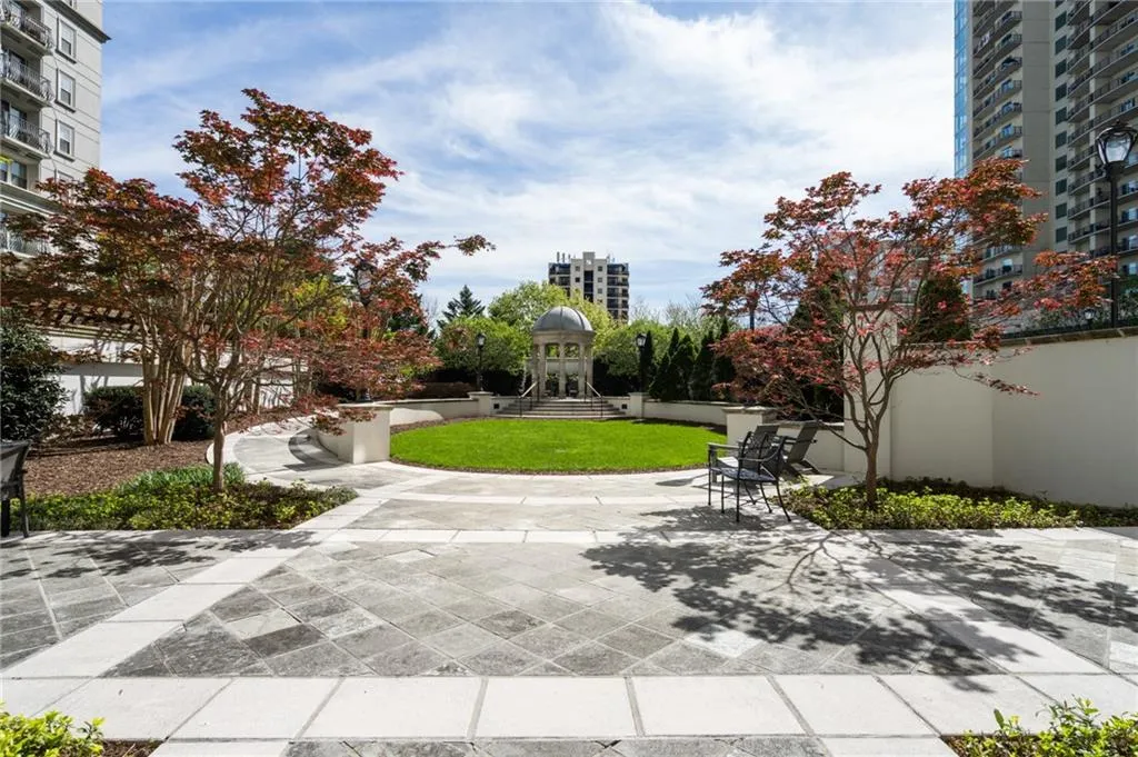 Landscaped courtyard featuring a central grass circle, mature trees, a decorative gazebo, and contrasting stone paving