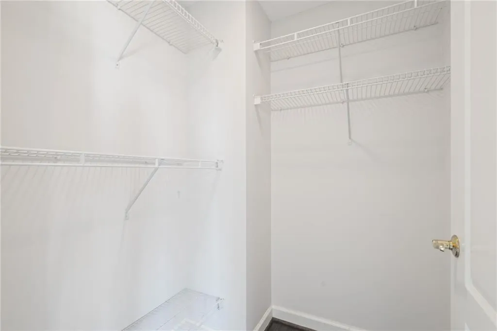 Open closet featuring multiple wire shelving units, a hanging rod, white walls, and dark wood-finish flooring
