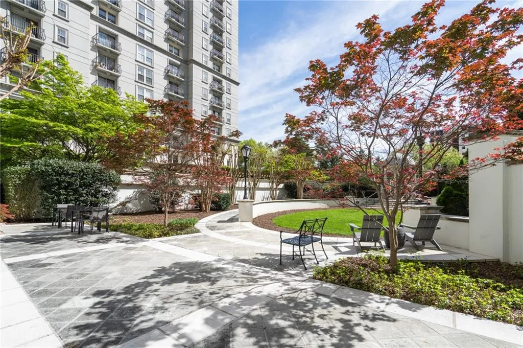 Landscaped courtyard featuring a patterned stone patio, manicured lawn, and mature ornamental trees