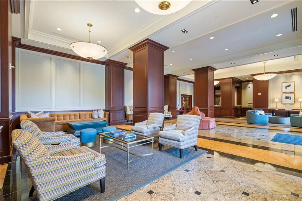 Spacious common area featuring a multi-toned tile floor, wood-paneled columns, recessed lighting, and decorative wall paneling