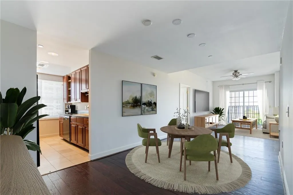 Open-concept living space featuring wood-finish flooring, recessed lighting, a ceiling fan, and a balcony with black metal railing