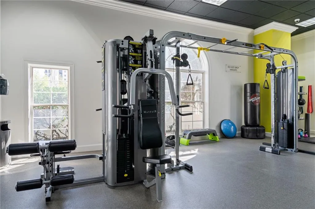Dedicated fitness area featuring multi-station gym equipment, arched windows, and durable rubber flooring