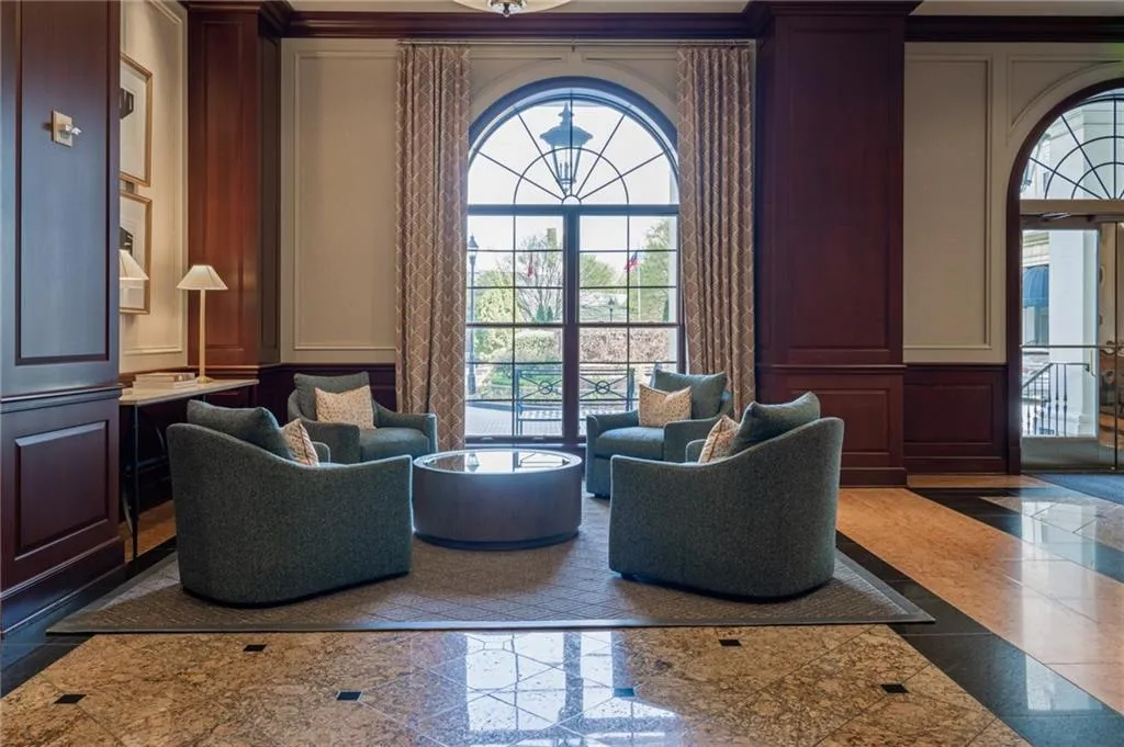 Arch-top windows with custom drapery, dark wood paneling, and wainscoting frame a seating area with a circular coffee table