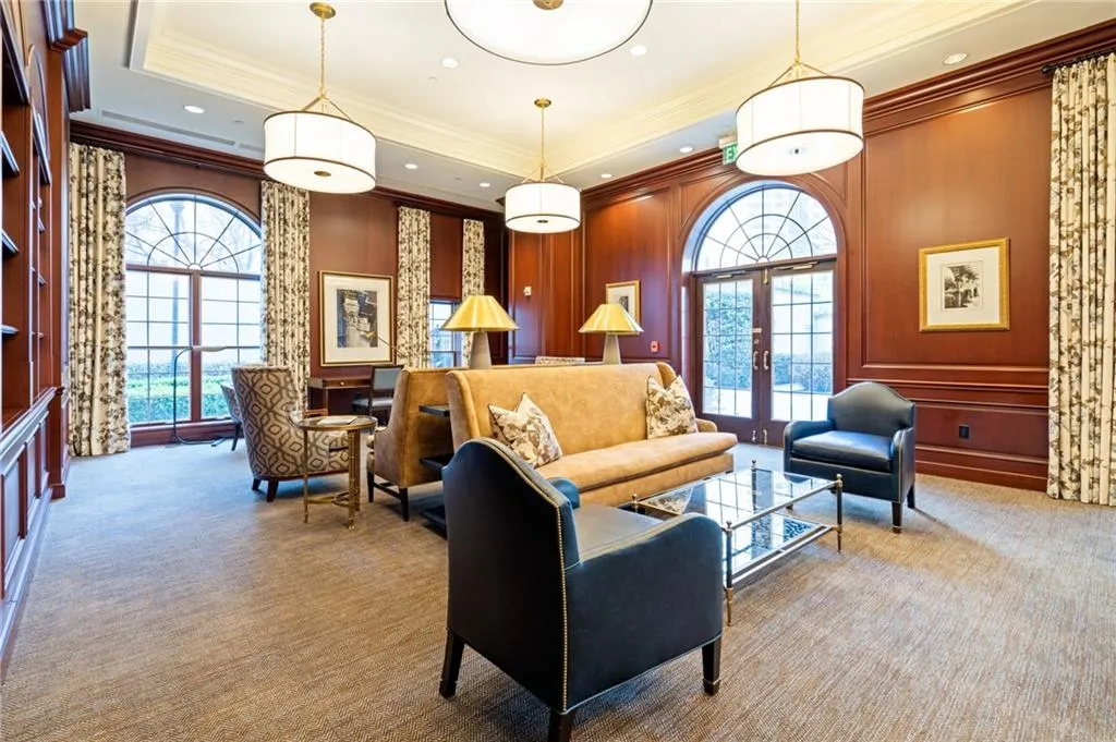Room featuring extensive wood paneling, built-in shelving, arched windows, and recessed lighting