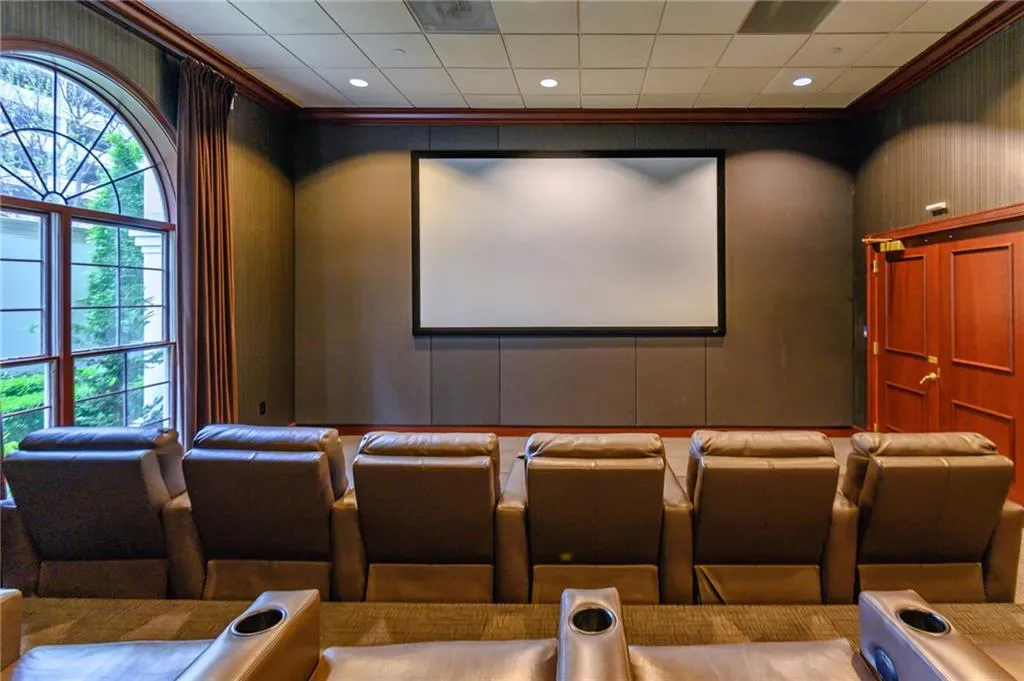 Dedicated media room featuring a large projection screen, dark wall paneling, and rich wood trim