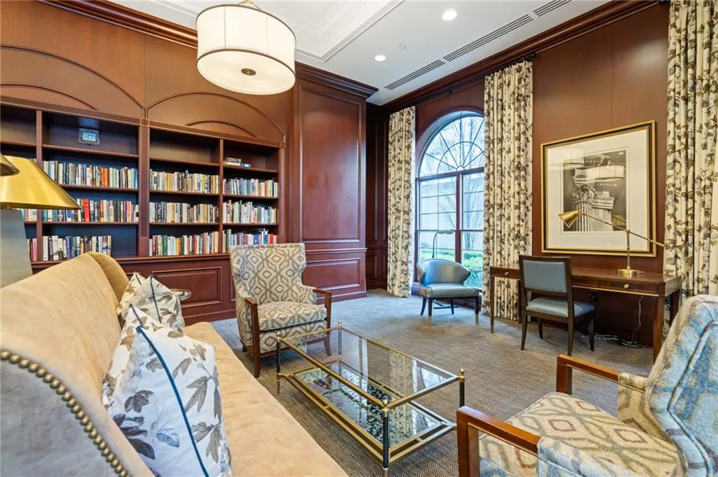 Room featuring extensive built-in mahogany shelving, a large arched window, recessed ceiling lighting, and detailed crown molding
