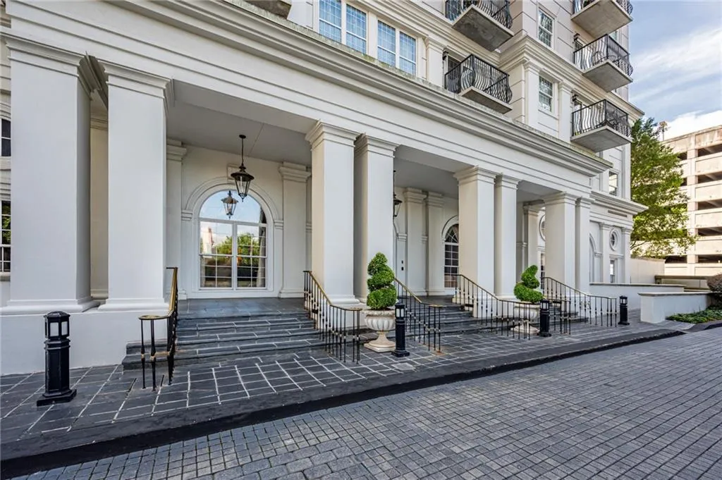 Grand entrance featuring a portico with large columns, stone steps, and wrought iron railings