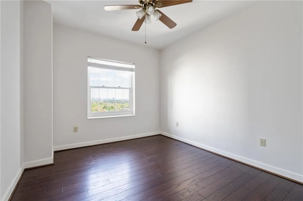 Room featuring wood-finish flooring, white baseboards, and a ceiling fan with light fixture