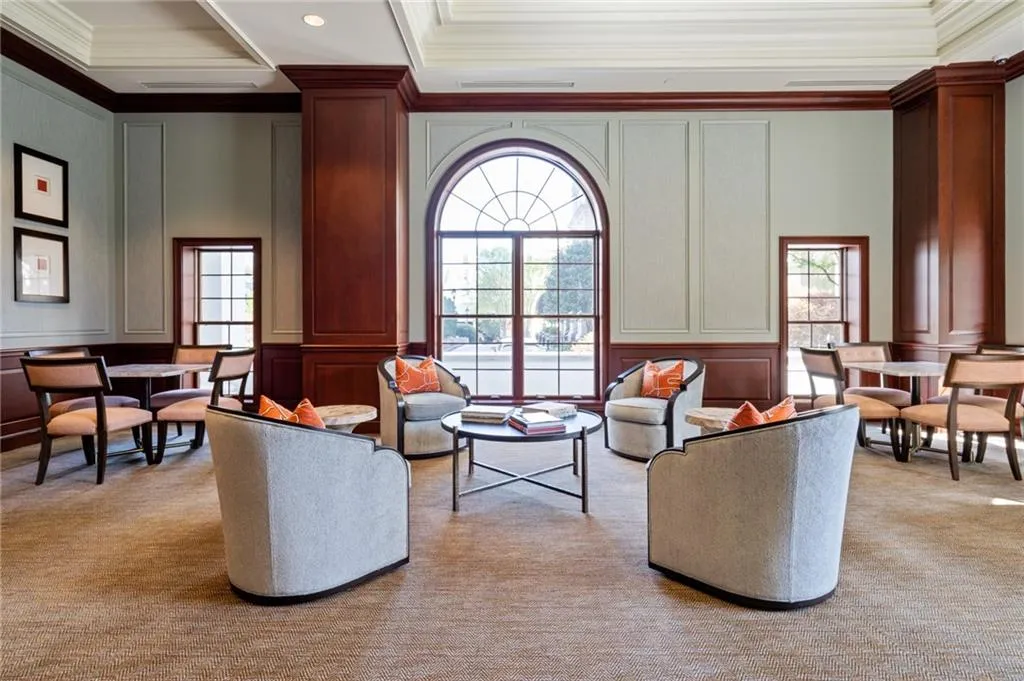 Lobby area featuring a grand arched window, warm wood paneling, decorative wall molding, recessed ceiling lights, and a textured carpeted floor
