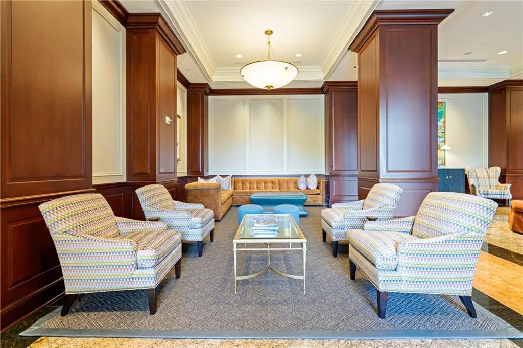 Lobby area featuring rich wood paneling, decorative wall molding, recessed lighting, and a central chandelier