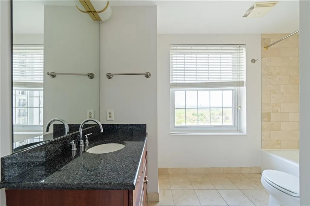 Bathroom featuring a double vanity with dark stone countertop, chrome fixtures, and undermount sinks