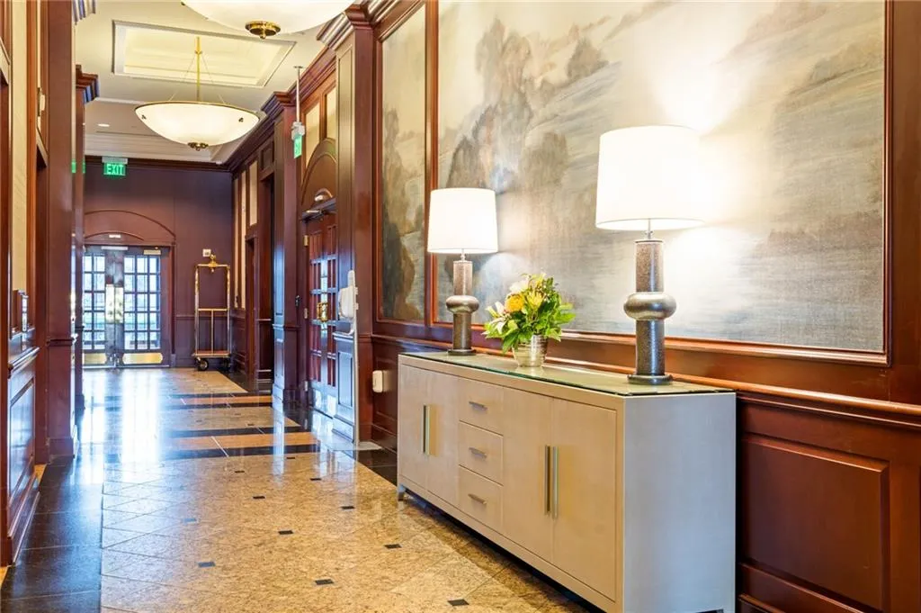 Hallway featuring rich wood paneling, decorative wall art, and polished stone flooring