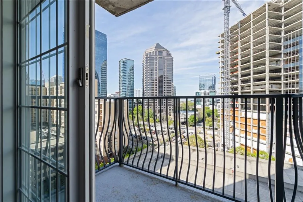 Private balcony featuring decorative wrought iron railing and concrete flooring, overlooking an urban landscape with multiple high-rise buildings and construction
