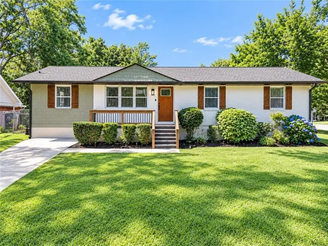 Ranch-style exterior with a gabled roof, mixed siding, a wooden entry door, and a concrete driveway