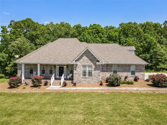 Brick exterior with a covered front porch, white columns, and a dark entry door