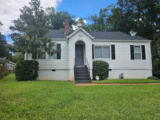 White siding exterior with black shutters, dark shingle roof, and a brick chimney
