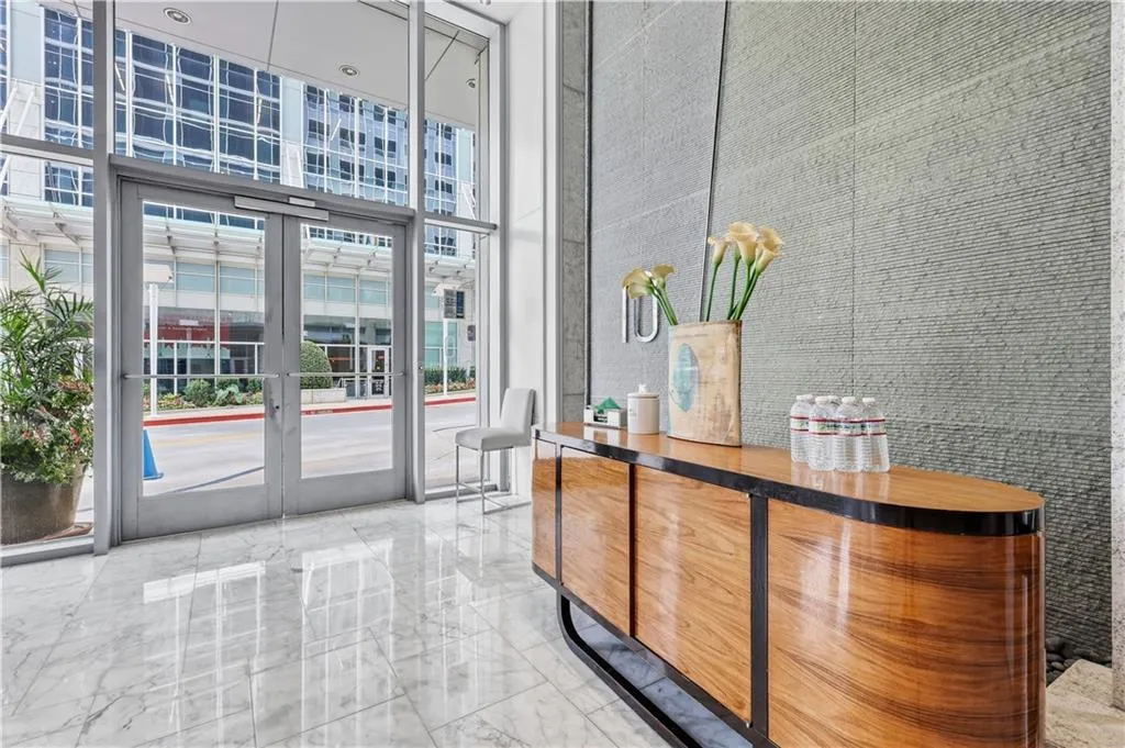 Polished stone flooring, expansive glass entry doors, and a textured accent wall